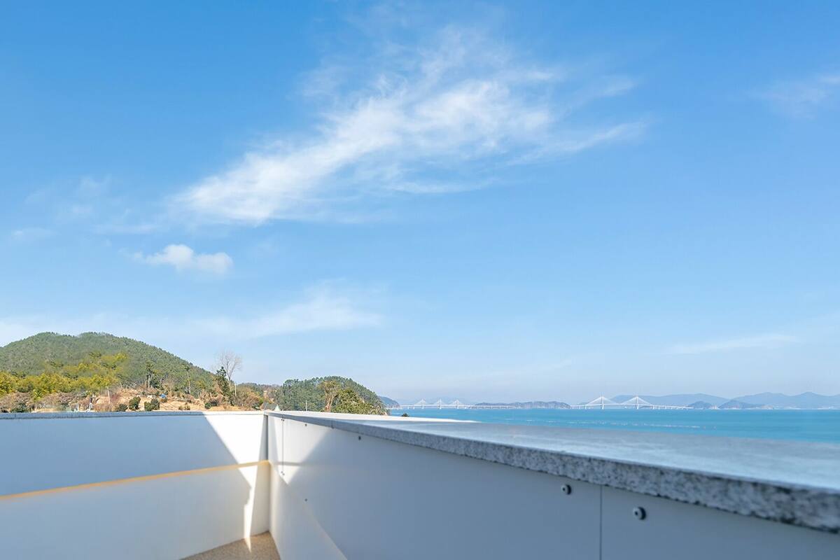 A balcony with a clear view of the sea and distant mountains.