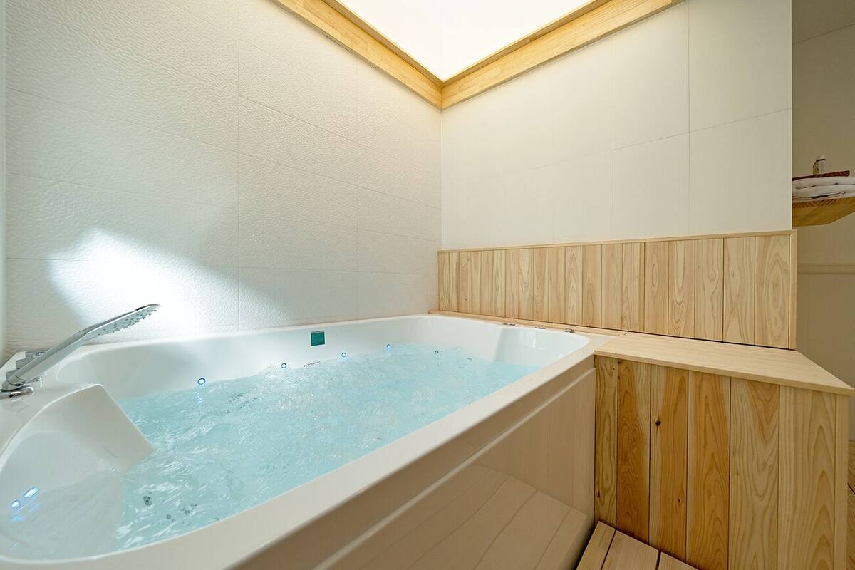 A modern bathroom with a freestanding bathtub, wooden paneling, and a skylight.