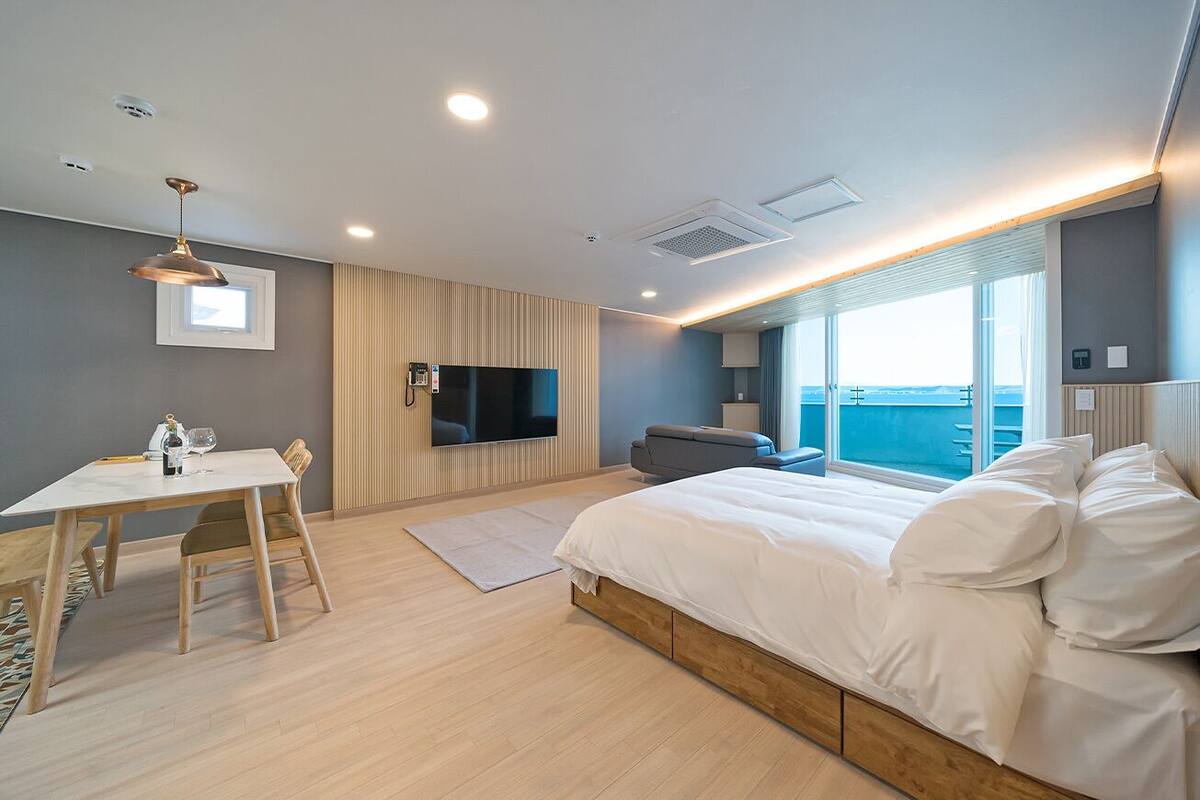 A modern hotel room with a large bed, a dining table, and a TV.