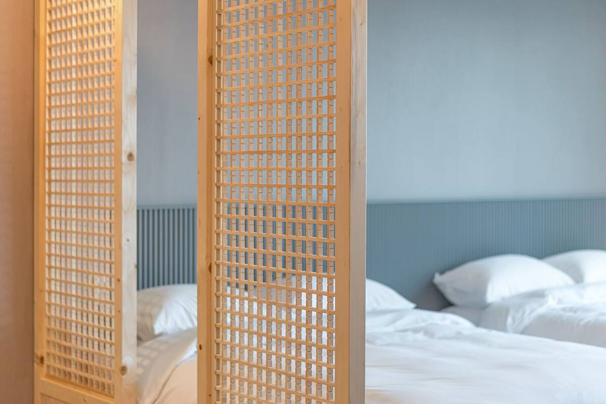 A hotel room with a bed, pillows, and a wooden partition.