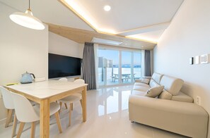 A modern living room with a dining area, a sofa, and a TV. - Oceanterra (Geoje)