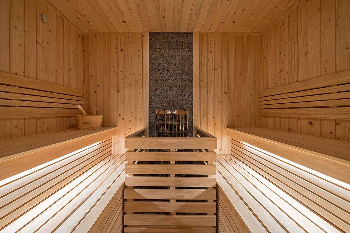 A sauna with wooden benches and a central stone wall.