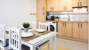 Une cuisine moderne avec des meubles en bois, un four encastré et un lave-linge.