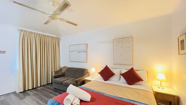 A hotel room with a bed, a chair, a ceiling fan, and a window with curtains. - 1 BR apartment at Glenelg Moseley (Glenelg)