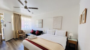 A hotel room with a bed, a desk, a chair, a ceiling fan, and a window with curtains. - 1 BR apartment at Glenelg Moseley (Glenelg)