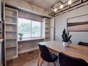 A modern dining area with a wooden table, black chairs, a potted plant, and built-in shelving.