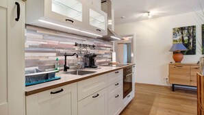 A modern kitchen with a wooden countertop, stainless steel appliances, and a glass backsplash.