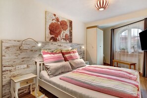 A bedroom with a bed, bedside tables, a painting, and a view of the outside. - 'Apartment Kaisereck Top 2' with Terrace & Wi-Fi (Reit im Winkl)