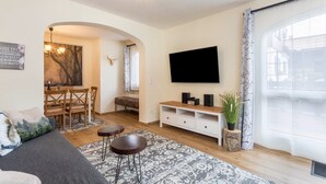 Uma sala de estar moderna com sofá, mesa de centro, televisão e área de jantar.
