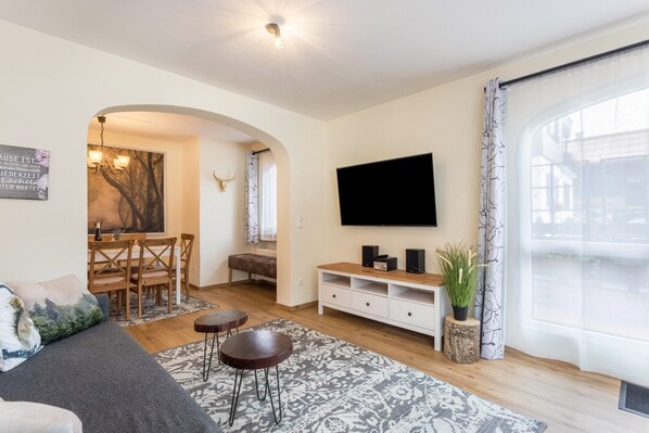 Un salon moderne comprenant un canapé, une table basse, un téléviseur et un coin repas.