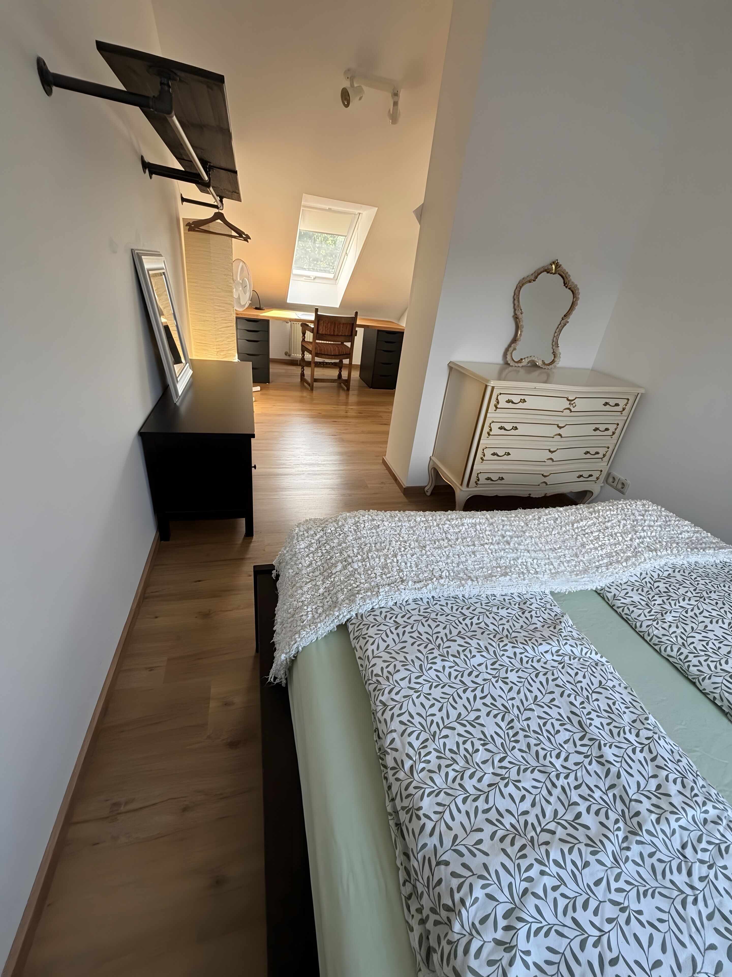 Une chambre à coucher comprenant un lit, une commode, une chaise et un bureau avec une autre chaise.