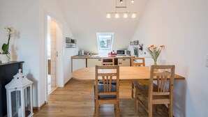 A modern kitchen with a wooden dining table, chairs, and a hanging light fixture.