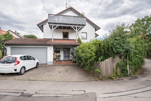 Une maison à deux étages avec un garage, un balcon et une allée.