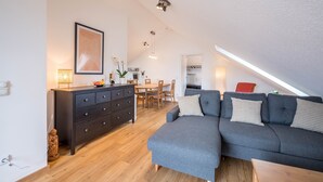 A modern loft apartment with a dining area, a gray sofa, and a wooden dining table.