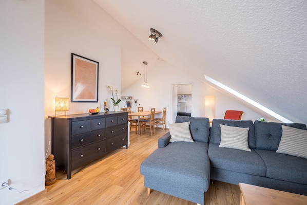 Moderni loft-tyylinen asunto, jossa on ruokailutila, harmaa sohva ja puinen ruokapöytä.