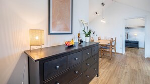 A modern kitchen with a dining area, wooden cabinets, and a hanging light fixture.