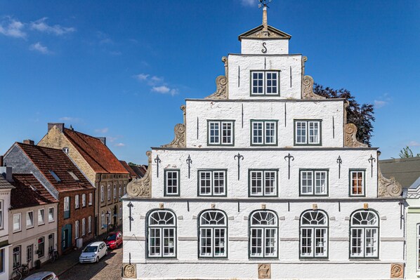 A multi-story building with a symmetrical facade, multiple windows, and a central tower with a weather vane.