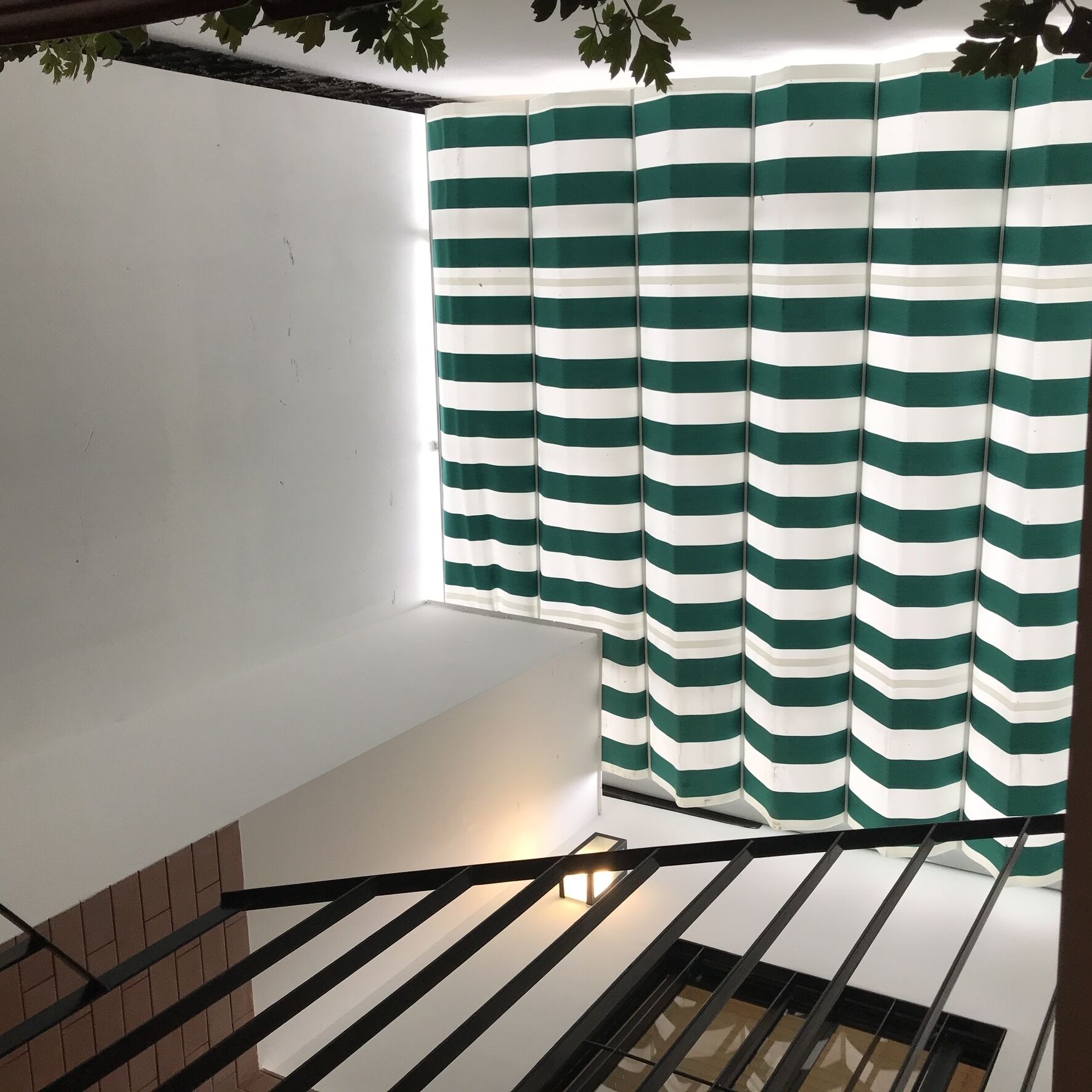 Una escalera con piso blanco y un tejido verde y blanco a rayas colgado.
