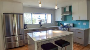 Una cocina moderna con electrodomésticos de acero inoxidable, una isla central y un ventanal que proporciona luz natural.