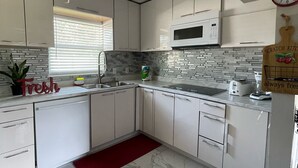 Eine moderne Küche mit weißen Schränken, einer Mikrowelle, einem Toaster und einem roten Teppich.