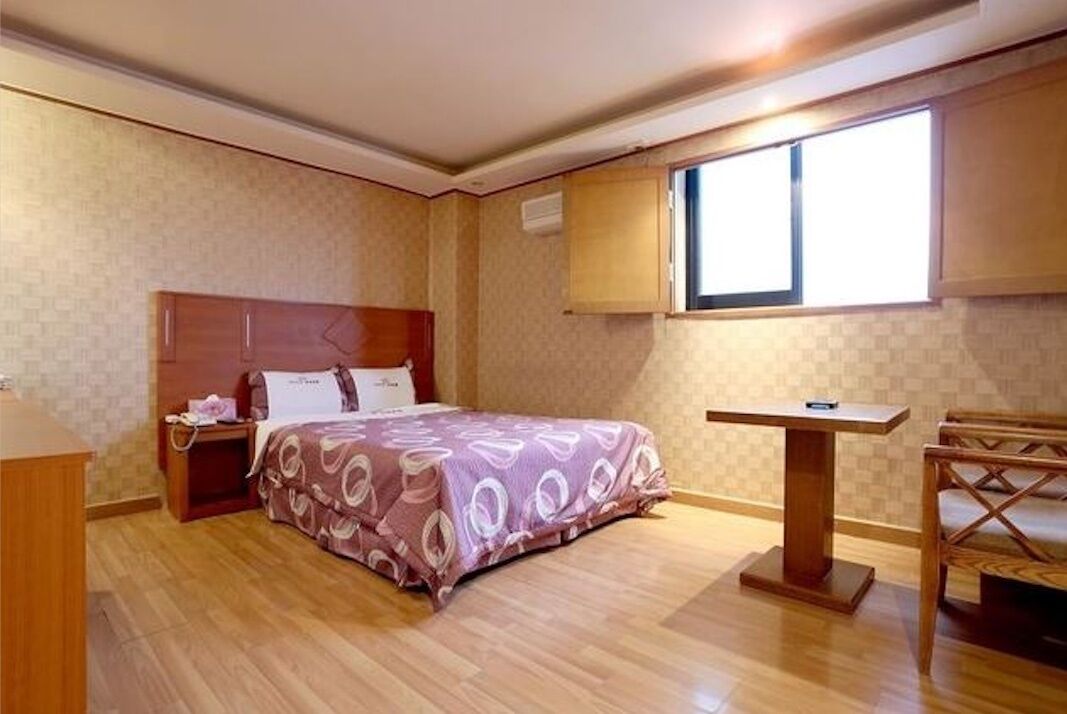 Un dormitorio con cama, mesita de noche y una pequeña mesa de madera.
