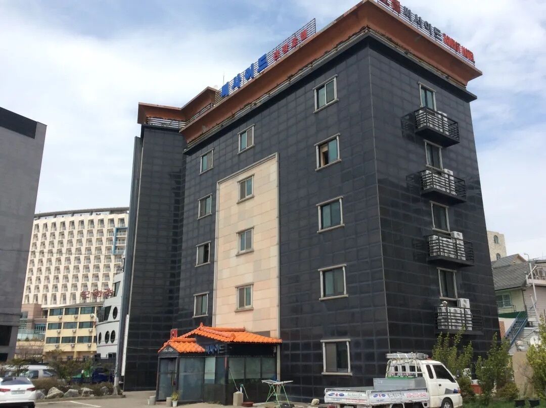 Un edificio de varios pisos con fachada oscura, múltiples balcones y un letrero que indica que es un hotel.