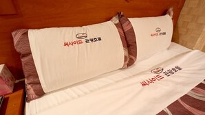 A bed with white bedding and pillows featuring Korean text. - Seaside Hotel (Incheon)
