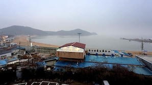 A coastal view with a beach, a cafe named "The Cafe," and a distant mountain. - Seaside Hotel (Incheon)