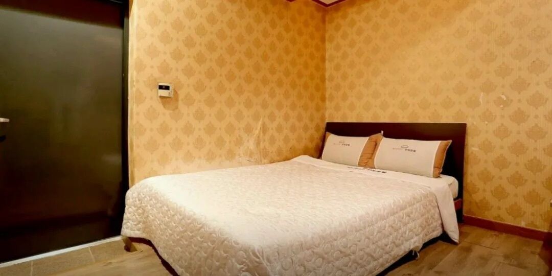 A neatly made bed with a patterned bedspread, a headboard, and two pillows.