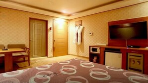 A hotel room with a bed, a desk, a chair, a television, and a microwave. - Seaside Hotel (Incheon)