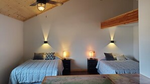 A bedroom with two beds, wooden ceiling beams, and wall-mounted reading lights. - Dream Drift Motel (Cameron)