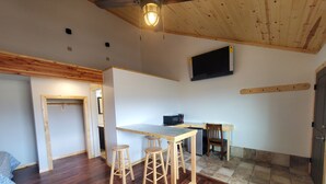A compact kitchen with a wooden countertop, two stools, a microwave, and a refrigerator. - Dream Drift Motel (Cameron)