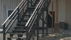 A building with a wooden staircase leading to a balcony. - Dream Drift Motel (Cameron)