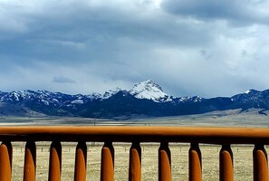 Cordillera nevada bajo un cielo nublado, vista desde un balcón con barandilla.