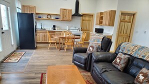 A compact living space with a dining area, a black leather sofa, and a wooden coffee table. - Dream Drift Motel (Cameron)