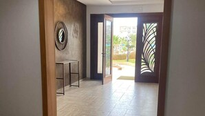 Un pasillo espacioso con suelo de baldosas, un marco de puerta de madera y un espejo fijado a la pared.