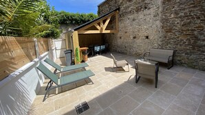 A patio with lounge chairs, a table, and a stone wall.