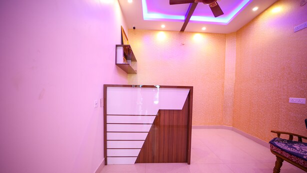 A room with a modern staircase, a ceiling fan, and a bench. - VR Inn (Puducherry)