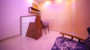 A room with a staircase, a bed, a chair, and a small table. - VR Inn (Puducherry)