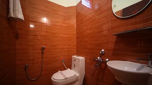 A bathroom with a white toilet, a sink, and a shower. - VR Inn (Puducherry)