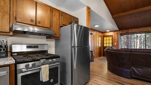 A modern kitchen with wooden cabinets, stainless steel appliances, and a wooden floor.