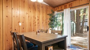 A wooden-paneled dining area with a table, chairs, and a plant.
