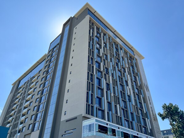 A tall, modern building with a symmetrical facade, large windows, and a prominent entrance at the base.