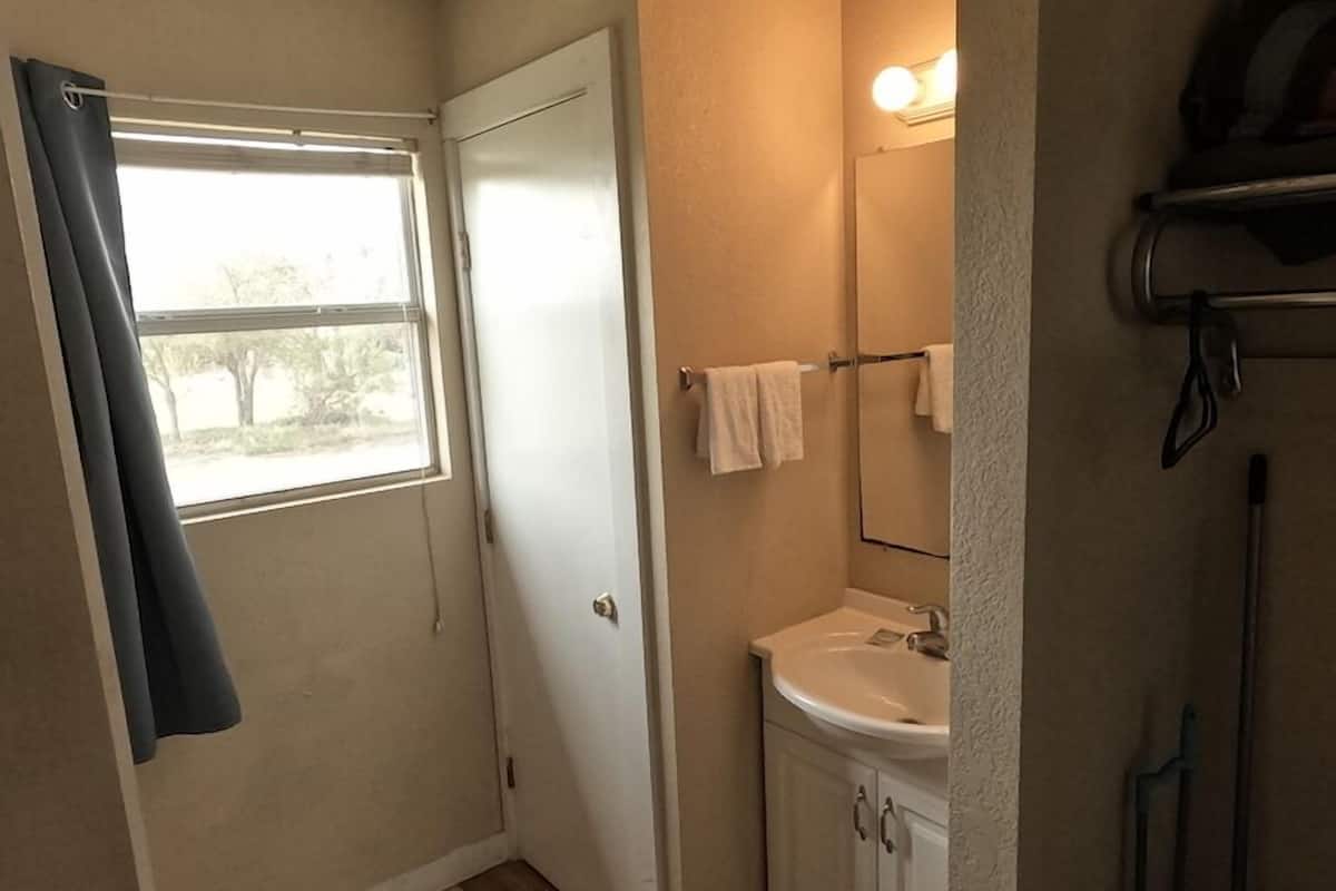 A small bathroom with a window, a sink, and a mirror.