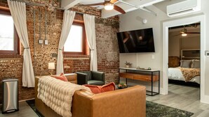 Ein modernes Wohnzimmer mit Backsteinwand, einer Couch, einem Schreibtisch und einem Fernseher.