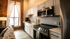 A modern kitchen with white cabinets, a stainless steel stove, and a microwave. - 2 Bedroom Townhouse Downtown Elkin Yadkin Valley (Elkin)