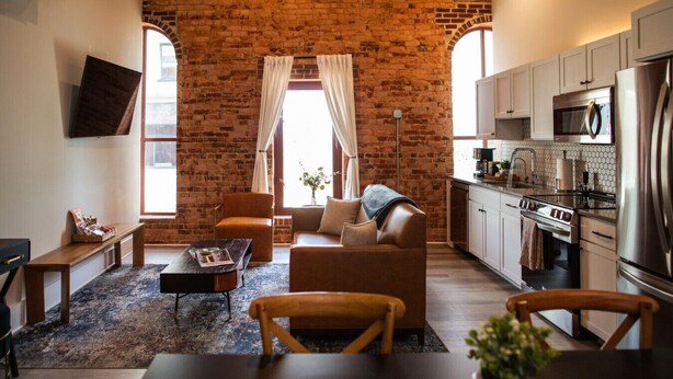 Un salon avec un mur en briques, un canapé, une table basse et un téléviseur fixé au mur.