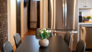 Una cocina moderna con electrodomésticos de acero inoxidable, una mesa de comedor con sillas y un jarrón con flores sobre la mesa.