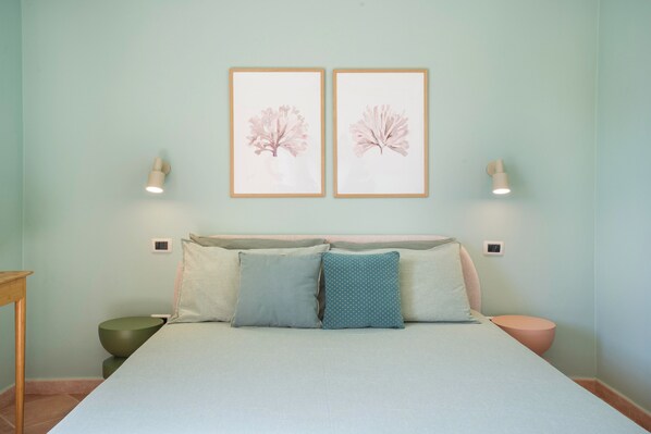 A bedroom with a bed, pillows, a bedside table, and two wall-mounted light fixtures.