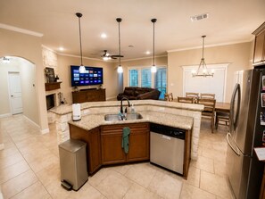 A modern kitchen with a granite countertop, built-in dishwasher, and a stainless steel refrigerator.